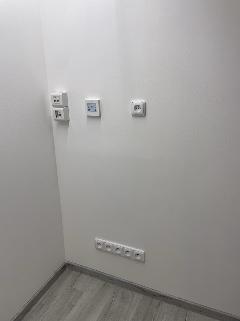 Zásuvky, datové porty a termostat instalované na stěně